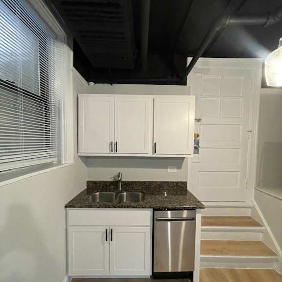 a small kitchen with white cabinets and a stainless steel sink