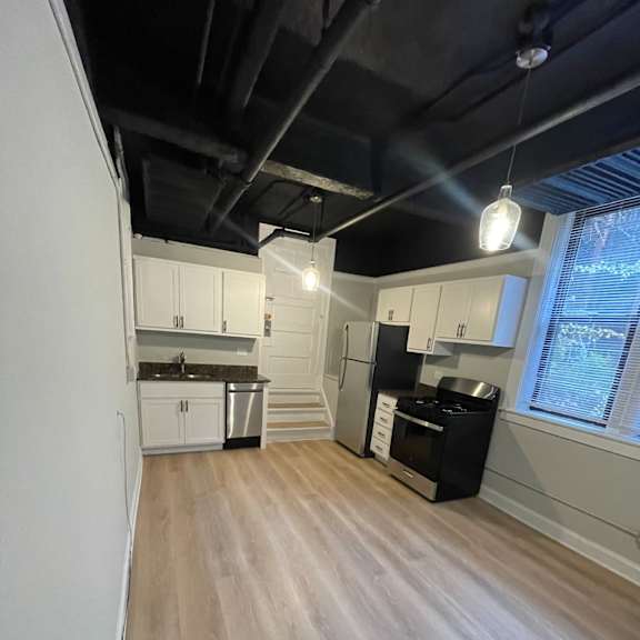 an empty kitchen with white cabinets and a black ceiling