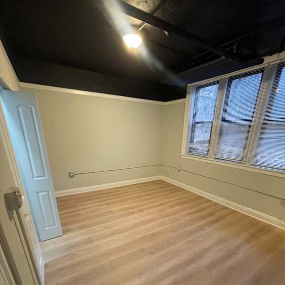 the living room of a house with wooden floors and a black ceiling