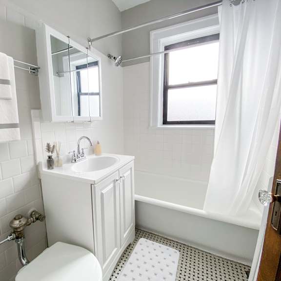 a white bathroom with a toilet, sink, and bathtub.