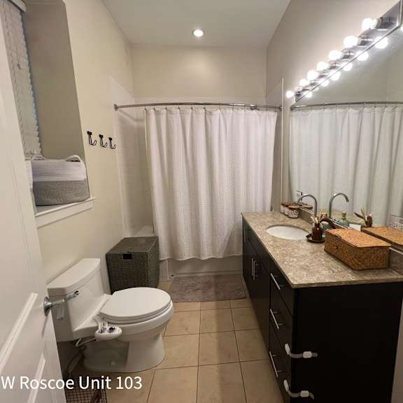 a bathroom with a toilet, sink, and shower curtain.