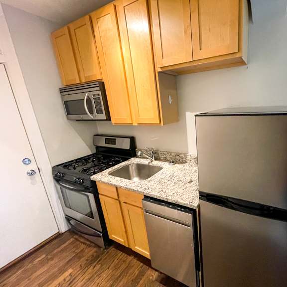 a kitchen with a black refrigerator, stainless steel sink, and wooden cabinets.
