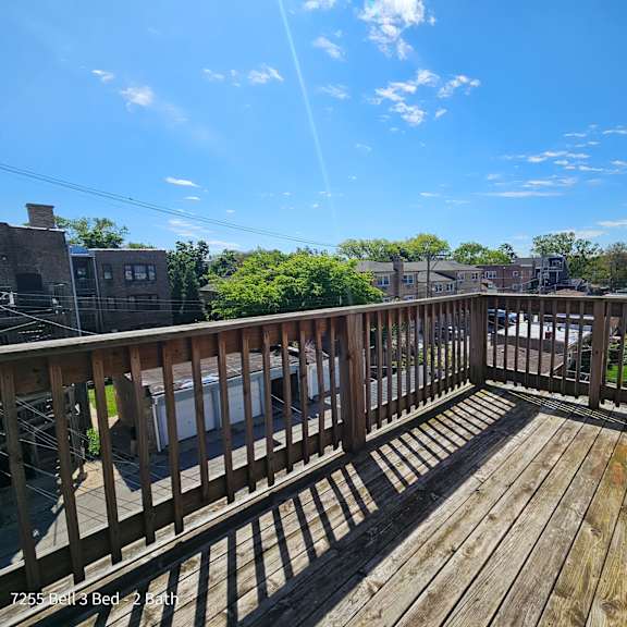 a balcony with a wooden deck and a blue sky