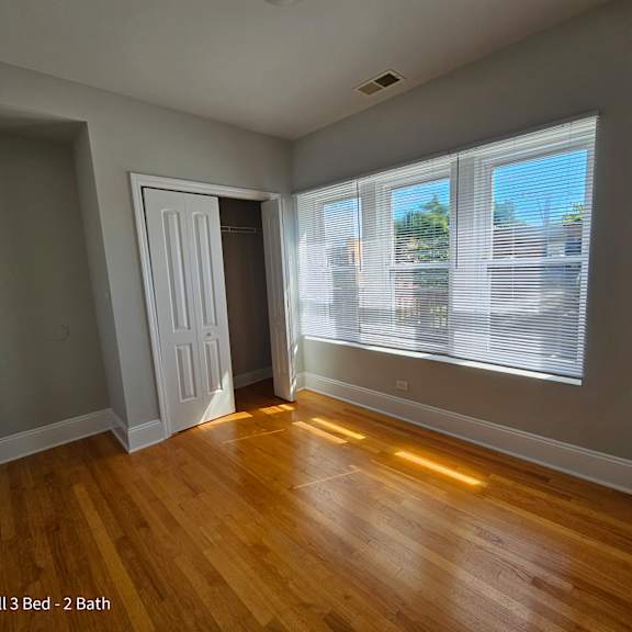 an empty living room with wood floors and a large window