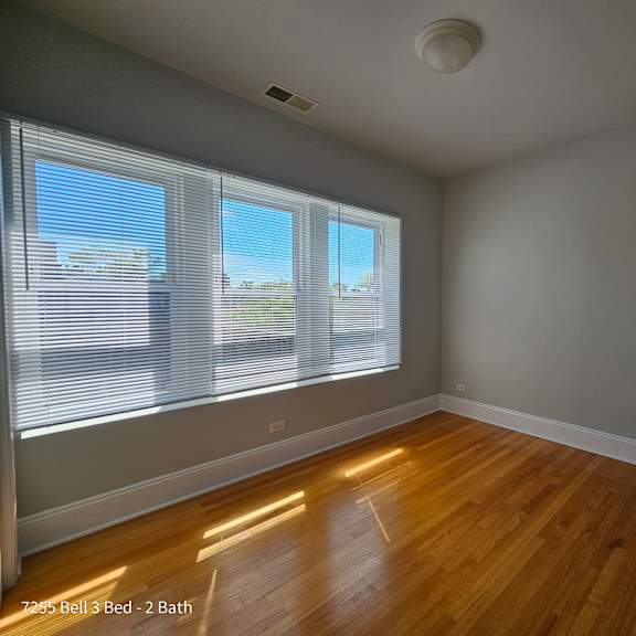 an empty living room with wood floors and large windows
