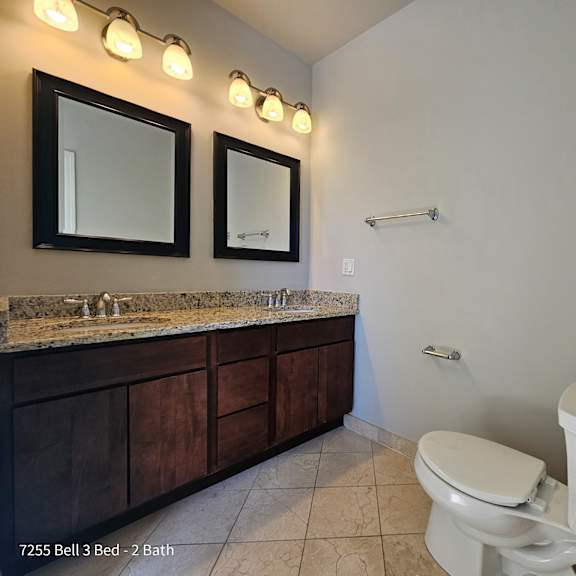 a bathroom with a toilet and a sink and two mirrors