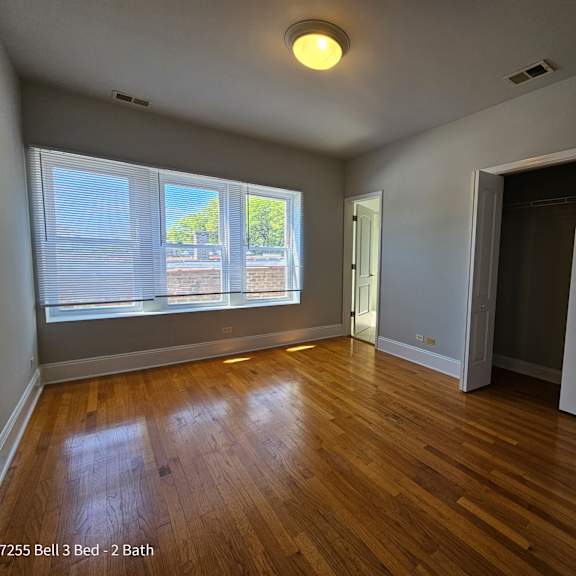 an empty living room with wood floors and a large window