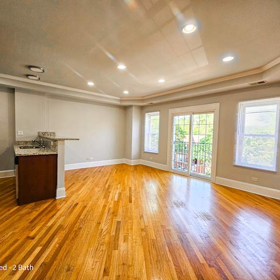 an empty living room with hardwood floors and a kitchen