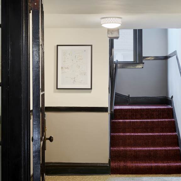 a staircase with a red carpet and a white framed picture on the wall.