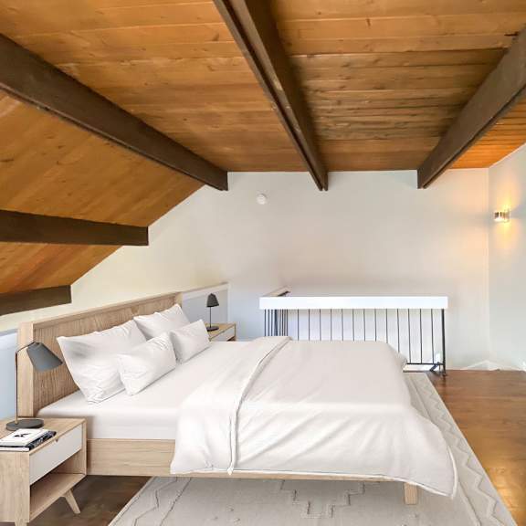 a bedroom with a bed, nightstand, and a wooden ceiling.