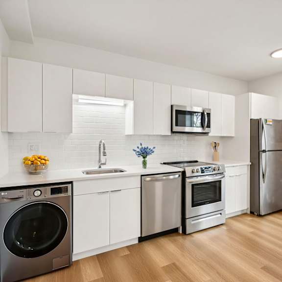 a modern kitchen with stainless steel appliances and white cabinets.