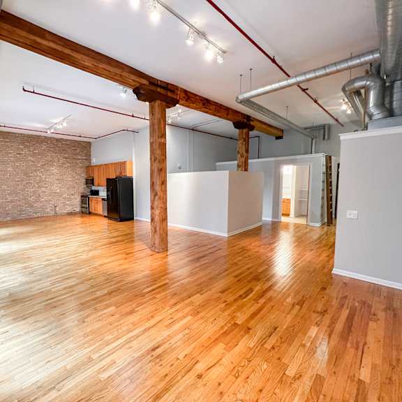 a room with wooden floors and exposed pipes.