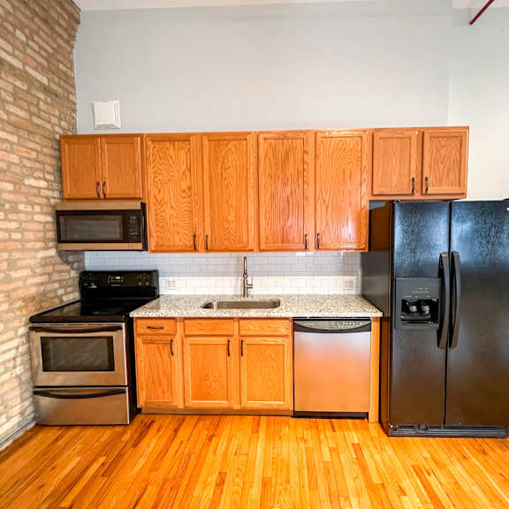 a kitchen with wooden cabinets and a black fridge.