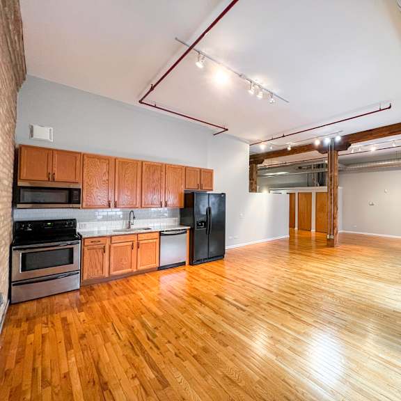 a kitchen with wooden floors and a brick wall.
