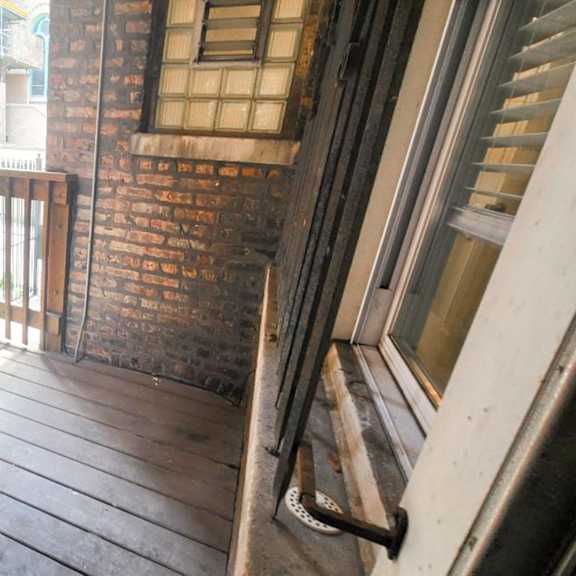 a wooden balcony with a metal railing and a door.