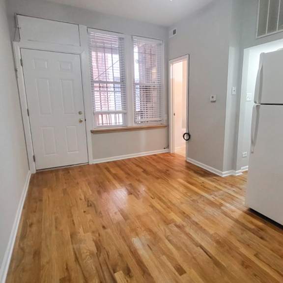a kitchen with a white fridge and wooden floors.