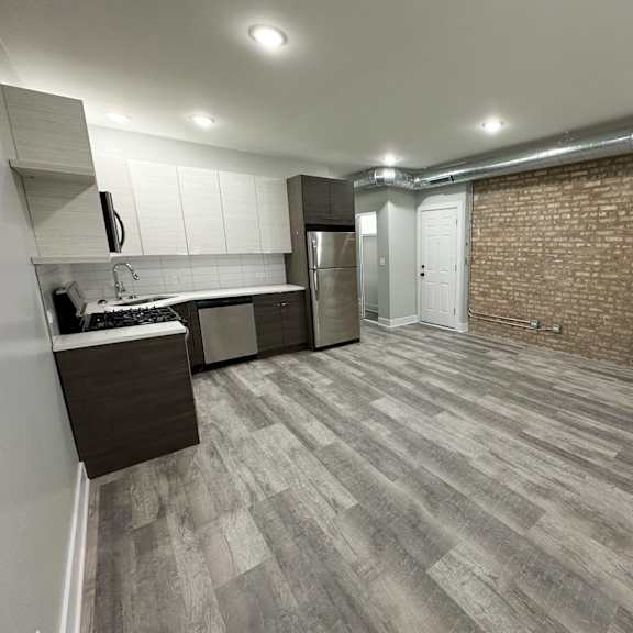 a kitchen with a refrigerator, sink, and cabinets.