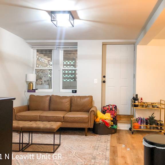 a living room with a brown couch and a black trash can.