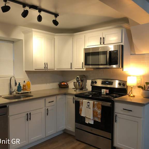 a kitchen with a black stove top oven and a black microwave above the stove.