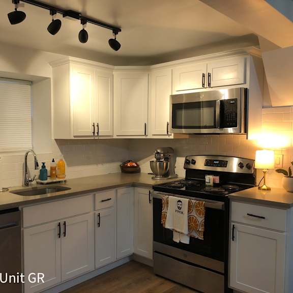 a white kitchen with stainless steel appliances and white cabinets