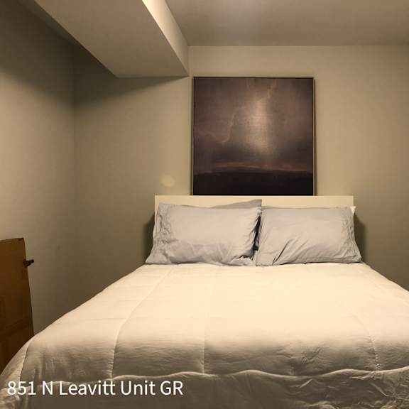 a bedroom with a bed, two pillows, and a painting on the wall.