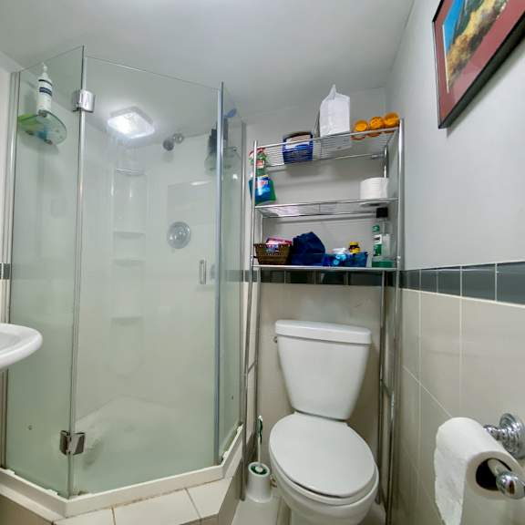 a white toilet is in a small bathroom with a sink and a shower.