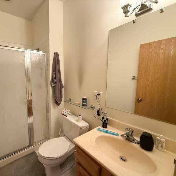 a bathroom with a toilet, sink, and shower.