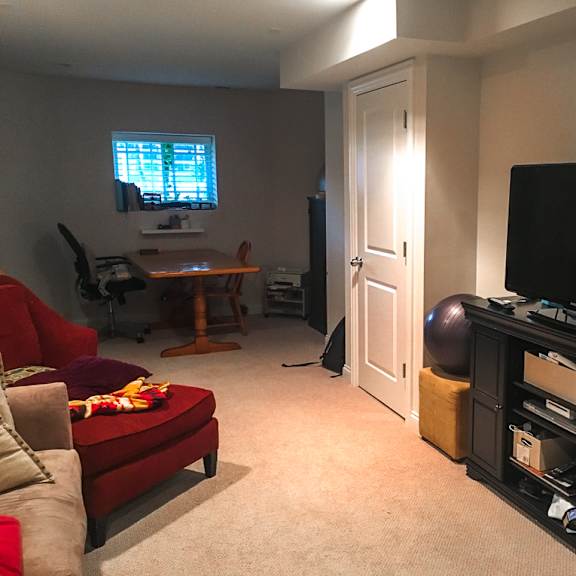 a living room with a red couch, a television, and a ball.