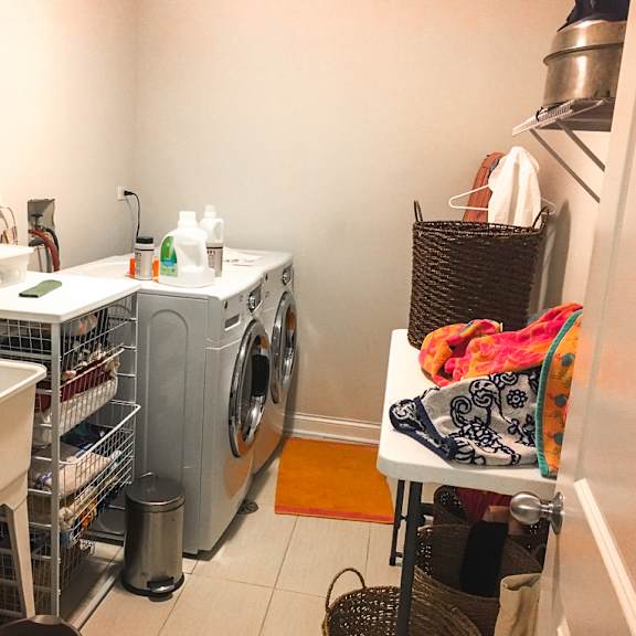a laundry room with a washer and dryer, a sink, and a basket of clothes.