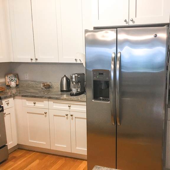 a kitchen with a stainless steel refrigerator and white cabinets.