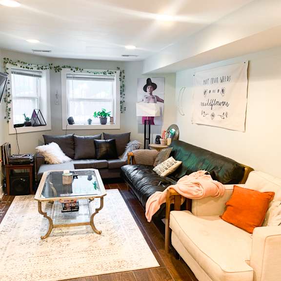 a living room with a white couch, a glass coffee table, and a television.