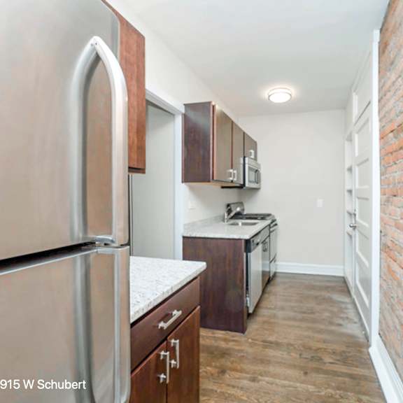 a renovated kitchen with a brick wall and stainless steel appliances