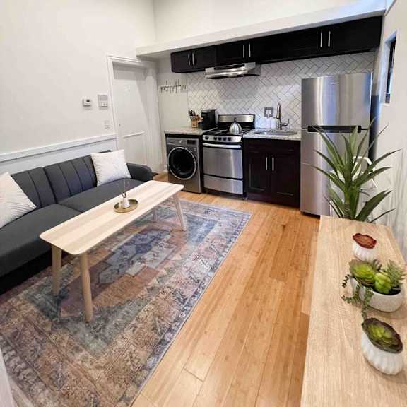 a modern kitchen with a grey sofa and wooden table.