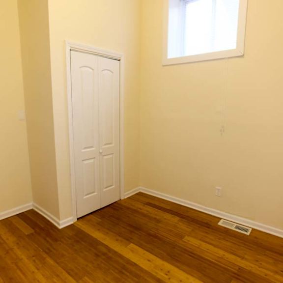 a room with a white door and wooden floor.