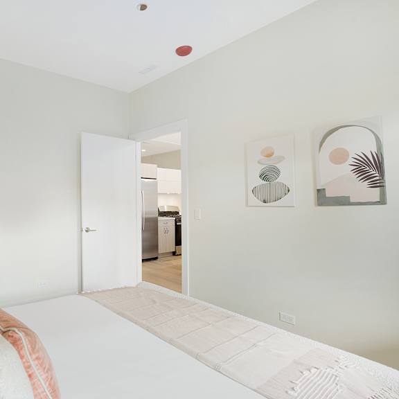 a white bedroom with a bed and a painting on the wall.