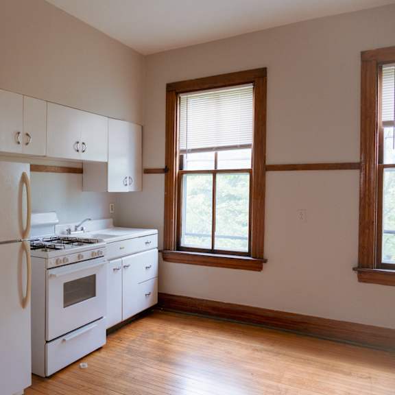 a white kitchen with a refrigerator, stove, and cabinets.