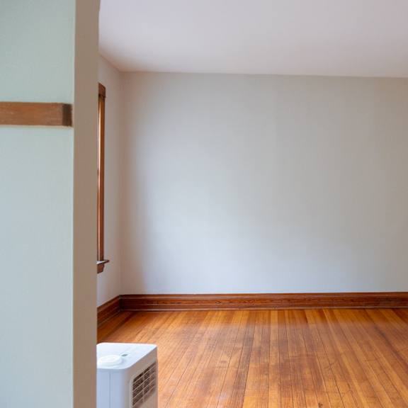 a room with a wooden floor and a white air conditioner unit.