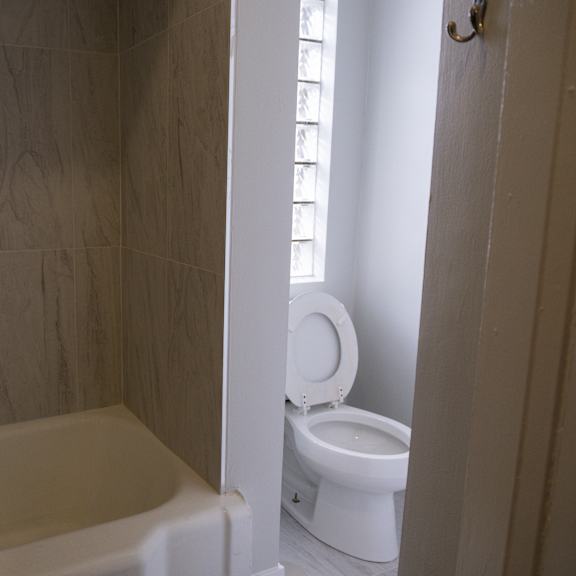 a white toilet is in a bathroom with a white tub.