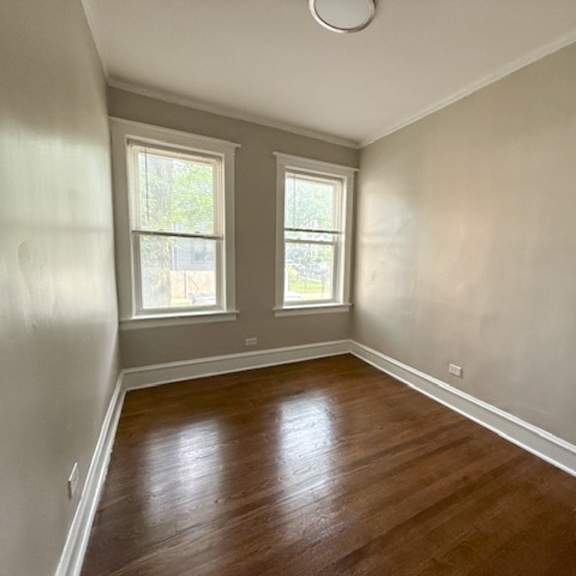 a room with wooden floors and two windows.