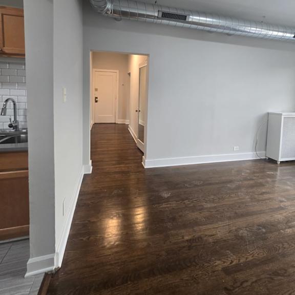 a long hallway with a white wall and a white floor heater.