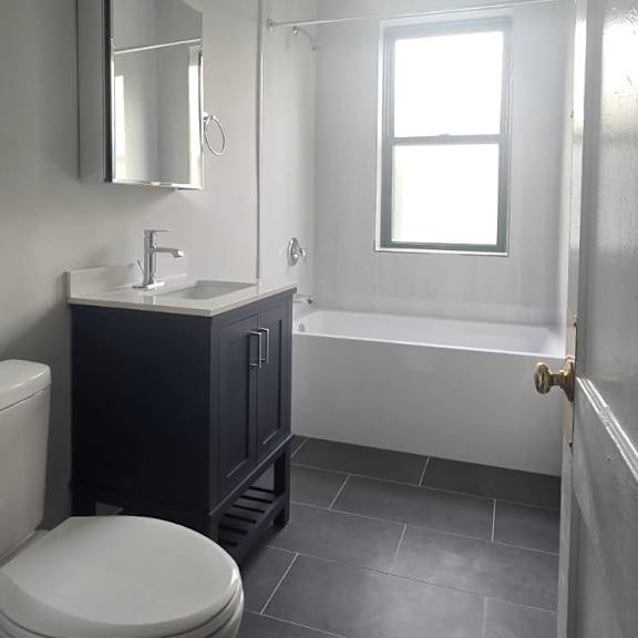 a white toilet sits in a bathroom with a black cabinet and a window.