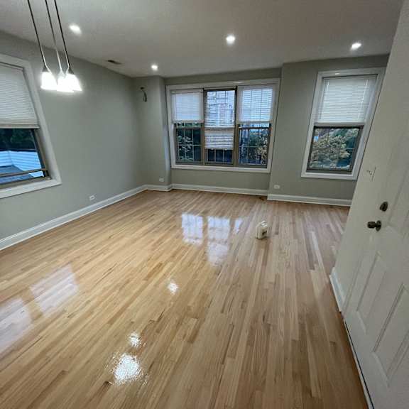 an empty living room with wooden floors and windows