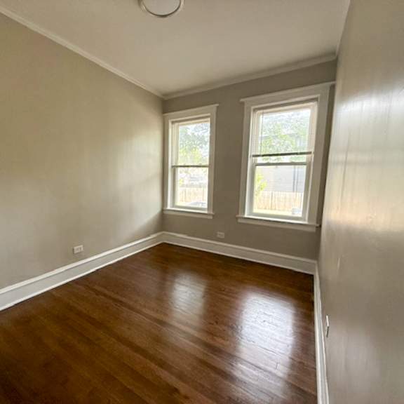 a room with wooden floors and two windows.