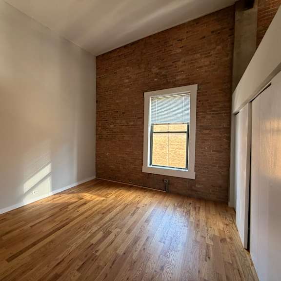 a room with wooden floors and a window with blinds.