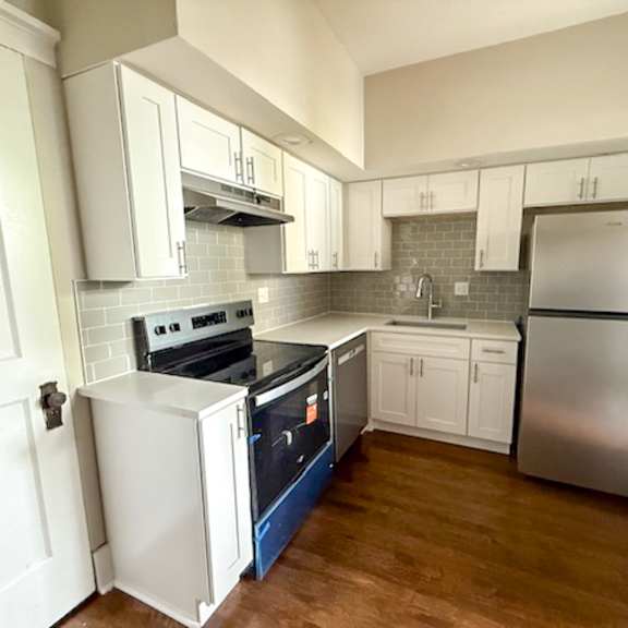 a kitchen with white cabinets and a stainless steel refrigerator.