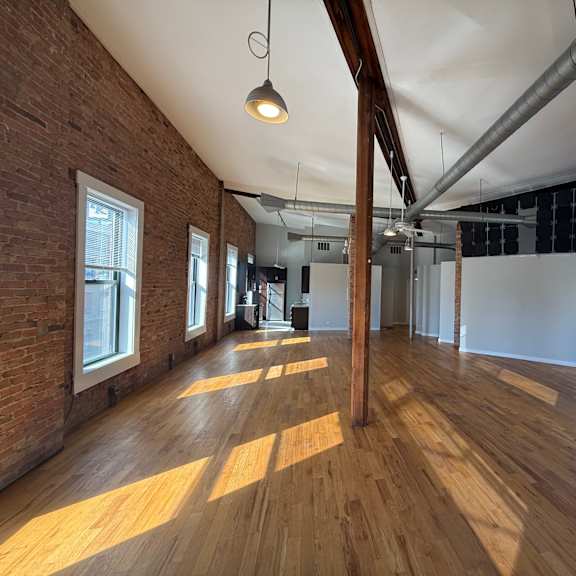 a large empty room with wooden floors and exposed ceiling beams.