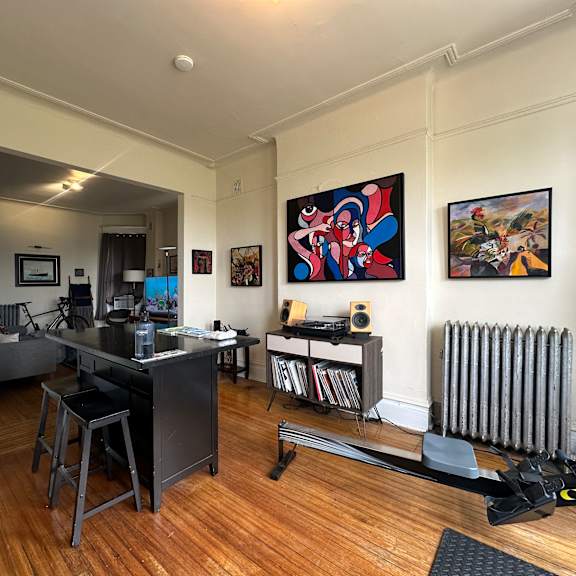 a room with a desk and a chair in front of a painting.