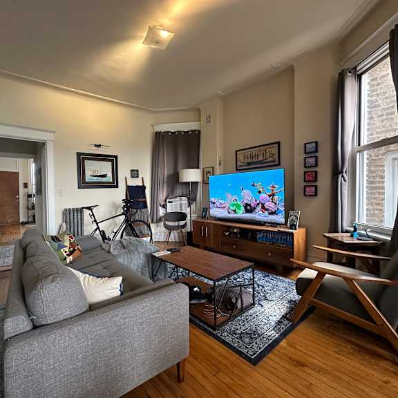 a living room with a grey couch and a television on a wooden cabinet.