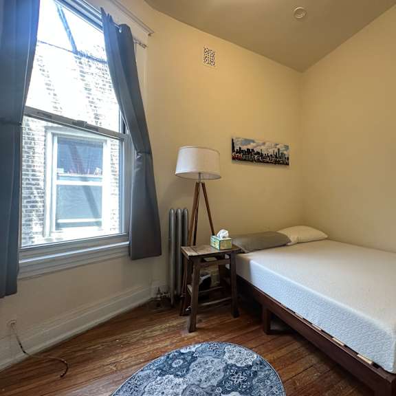 a bedroom with a bed, nightstand, and window.