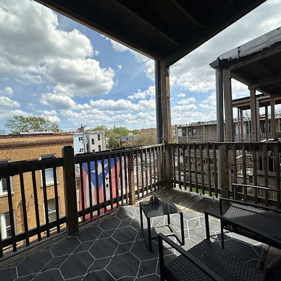 a balcony with a bench and a table with a view of the sky and buildings.